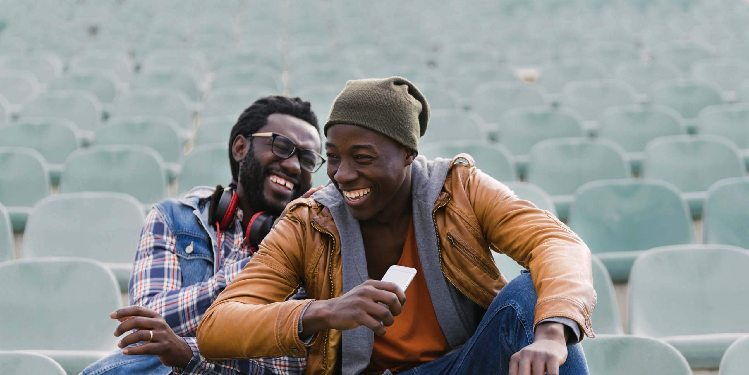 Two friends laughing in an empty stadium.