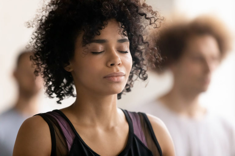 Black female with her eyes closed, meditating