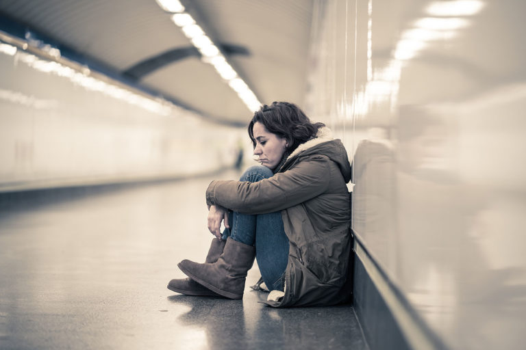 A lone individual in a subway tunnel, sitting on the floor